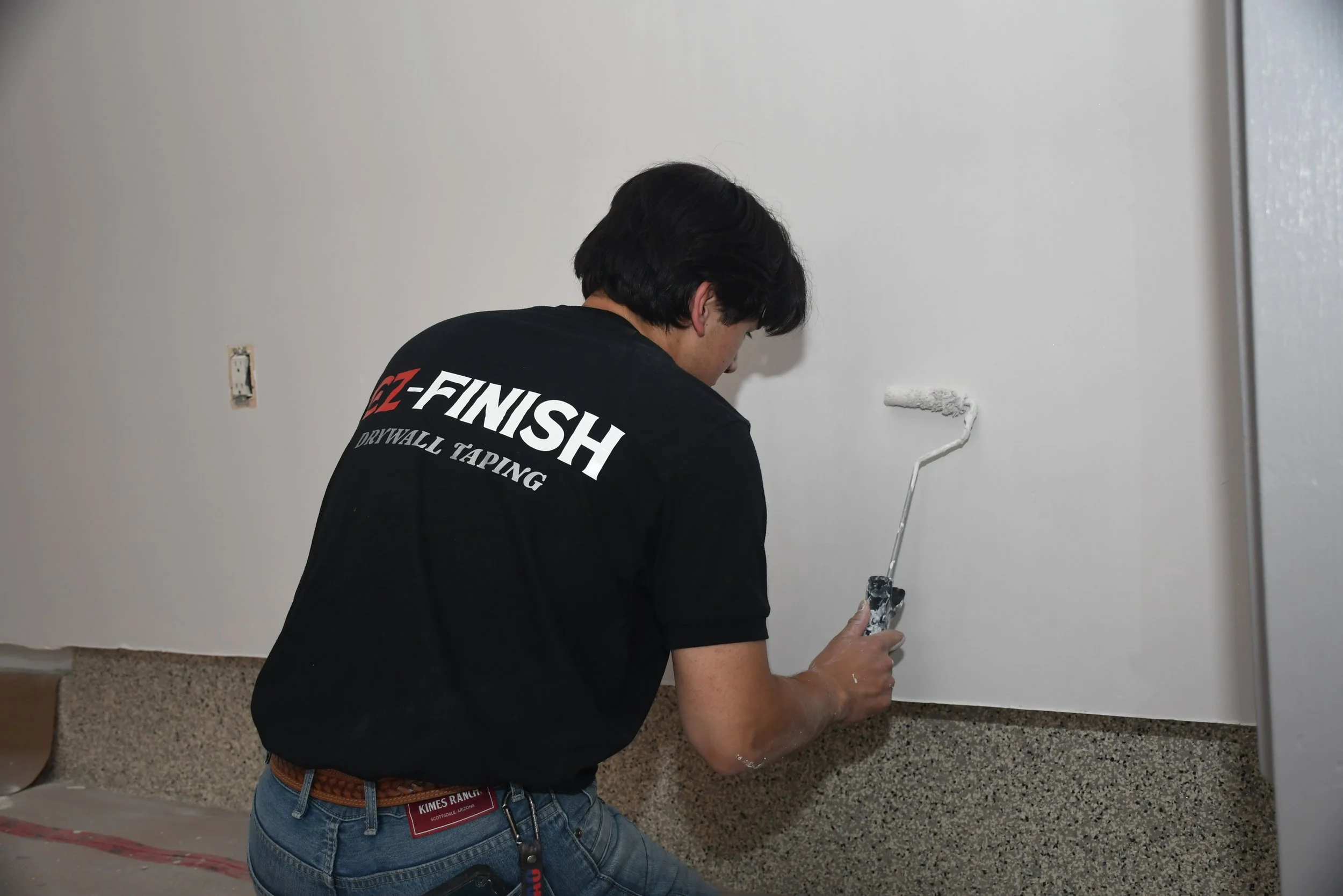 A person painting a wall with a roller brush.