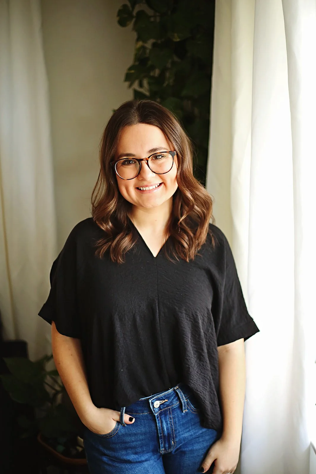 Speech-language pathologist Jenna Kahila, wearing a black shirt and blue jeans smiling indoors.
