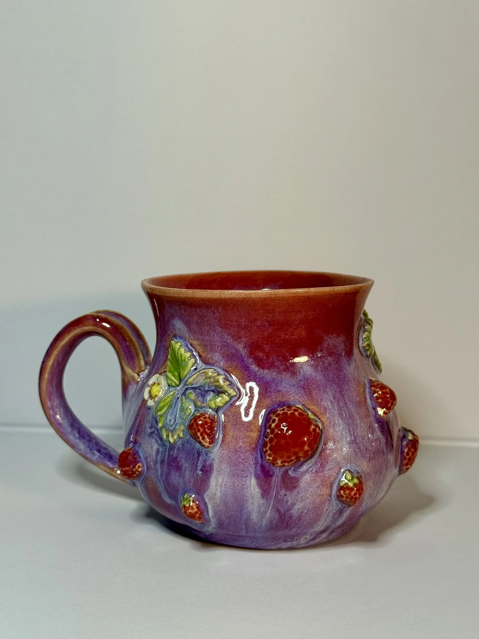 Decorative ceramic mug with a purple and pink gradient, adorned with 3D strawberry and leaf motifs on its surface.