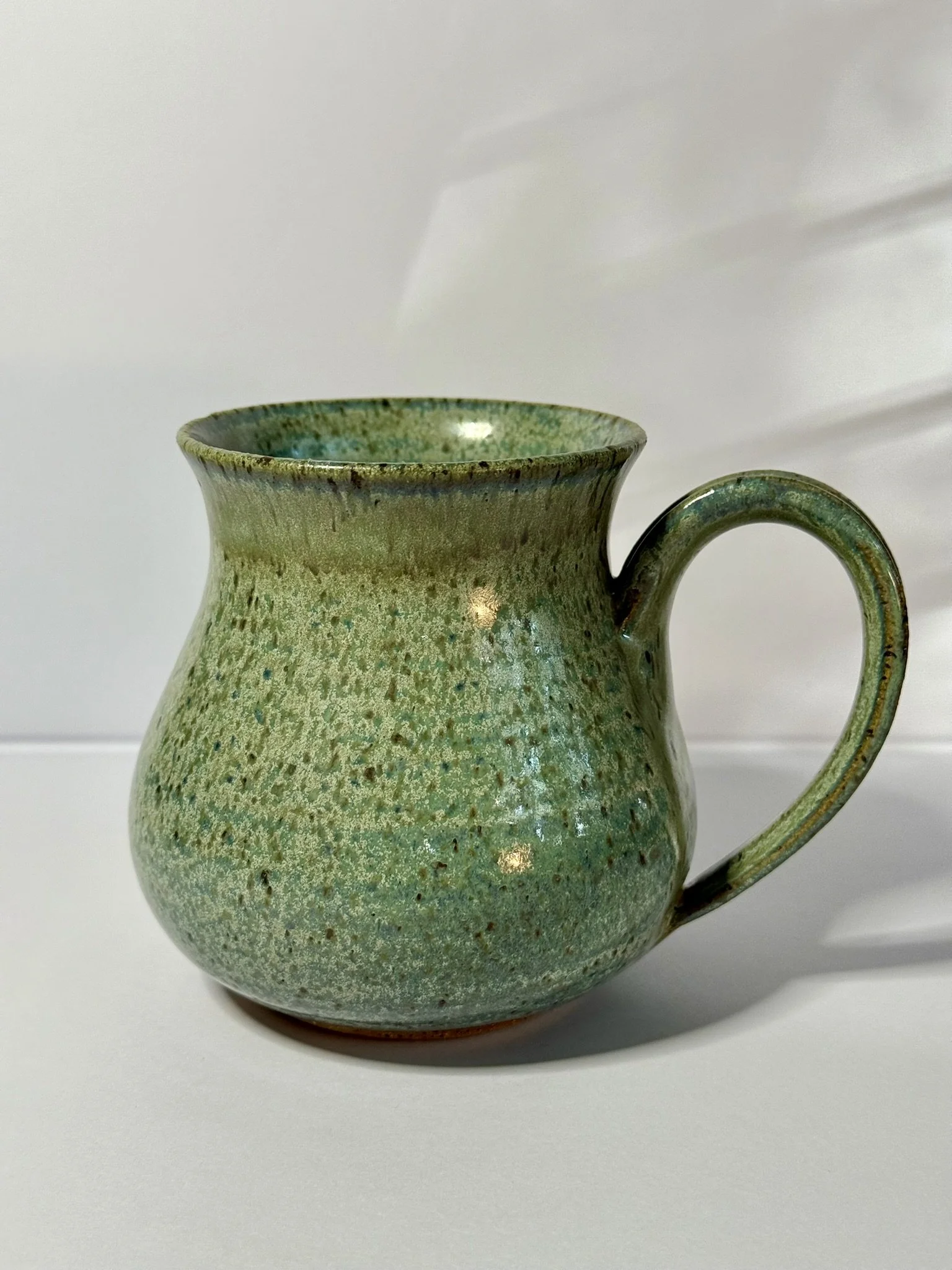 Green ceramic mug with textured surface on white background.