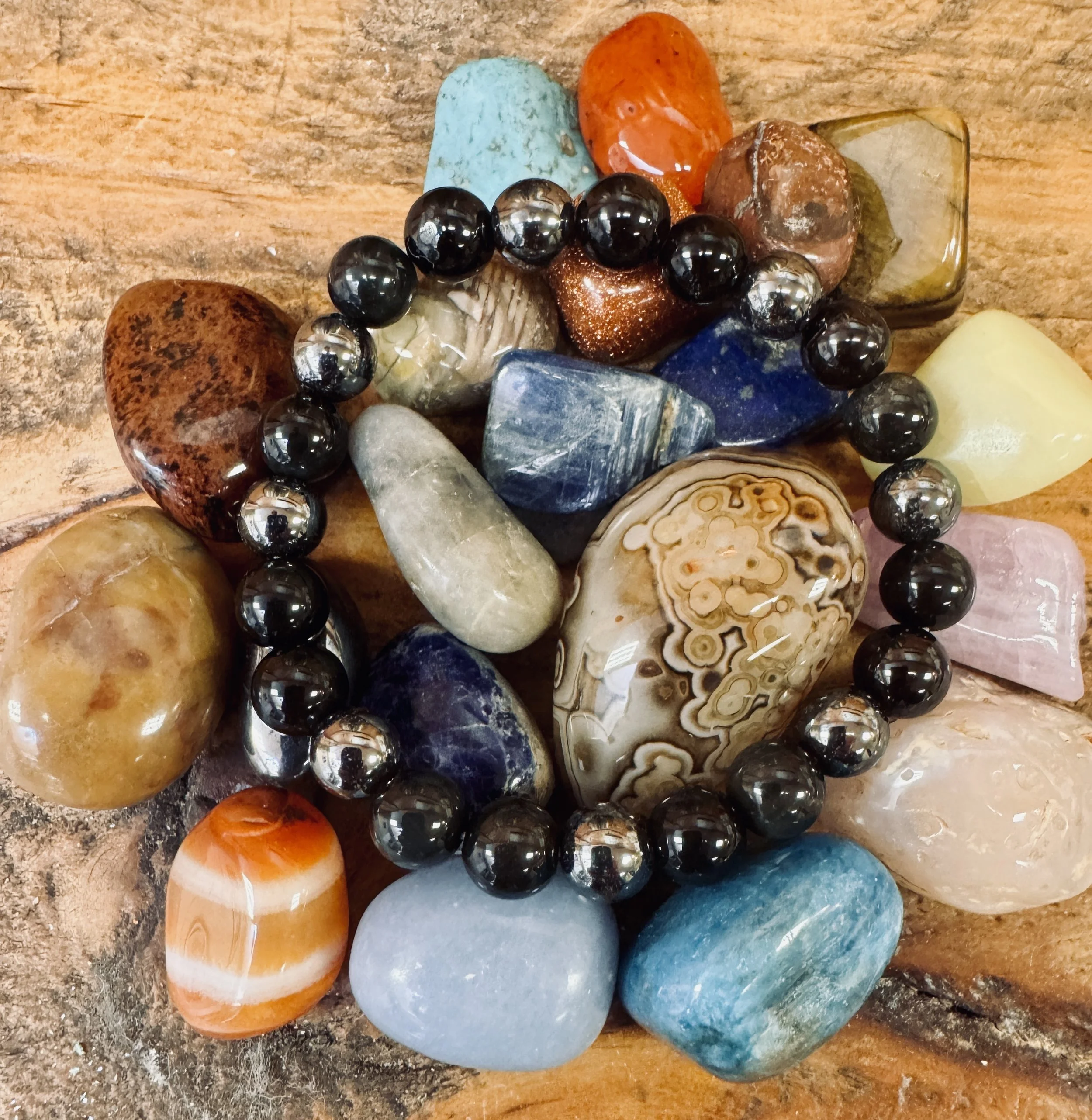 Collection of polished stones and beads on a wooden surface.