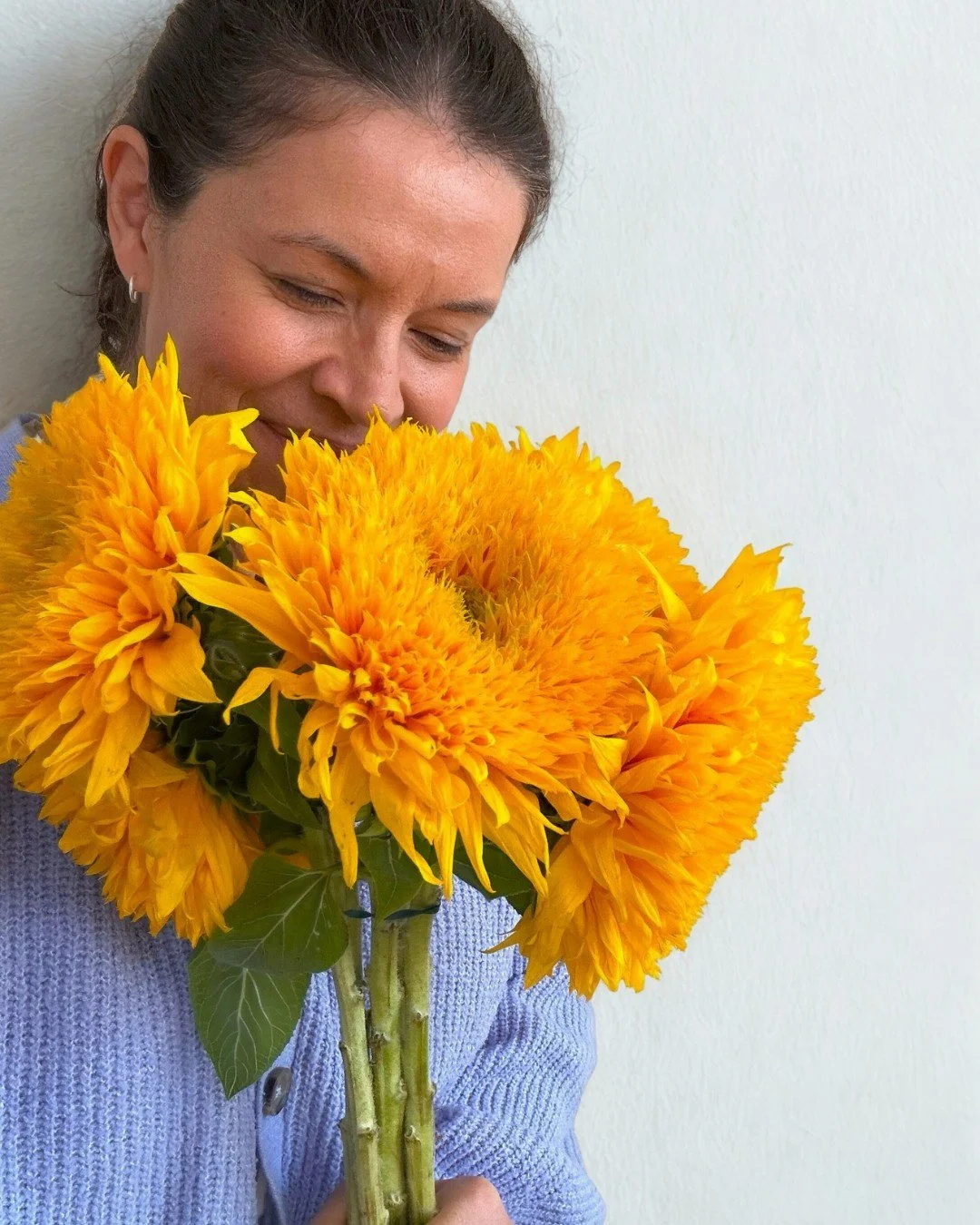 woman holding bunch of yellow sunflowers