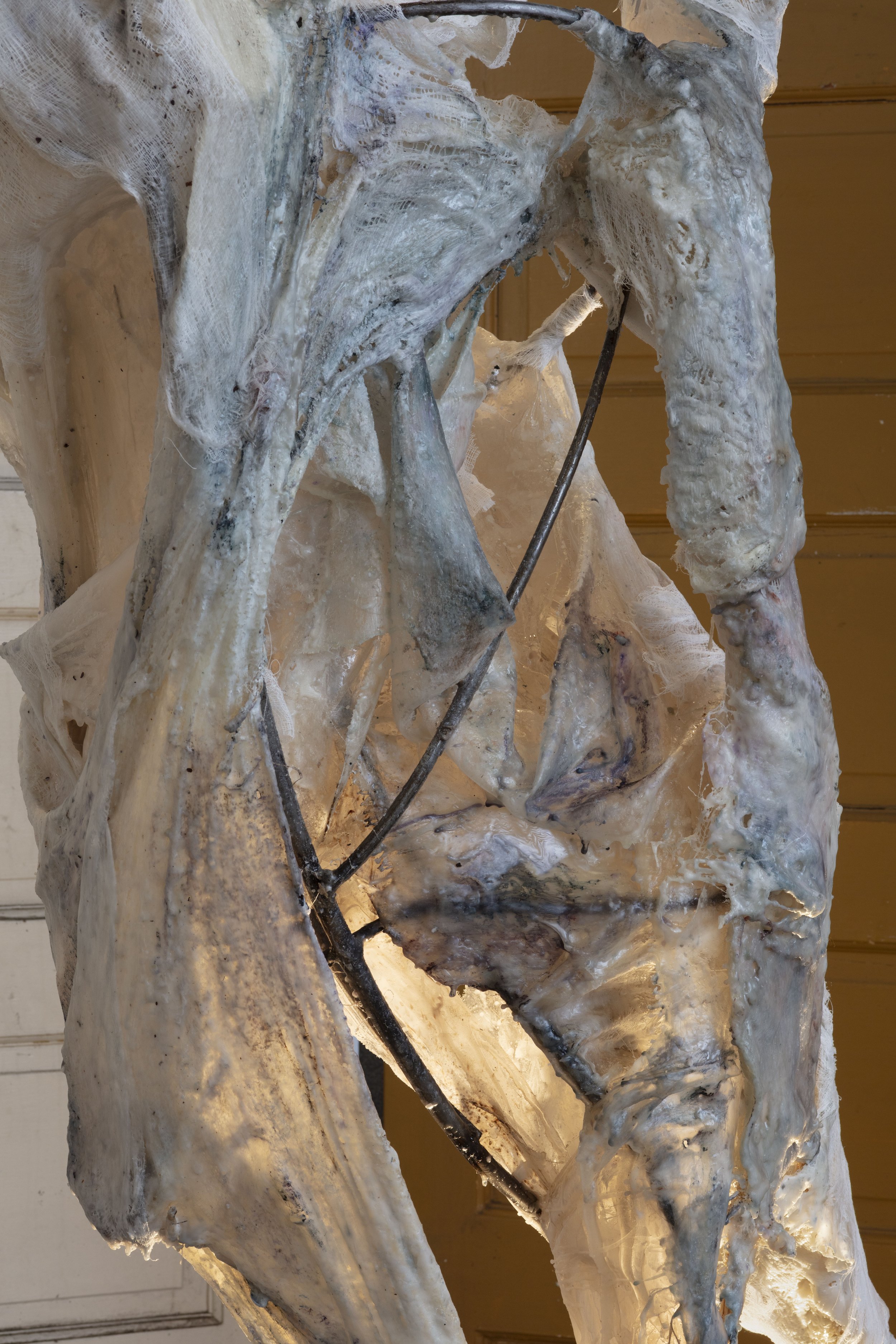 A frozen mountain landscape sculpture with ice formations and black metal rods, illuminated from below, against a wooden background.