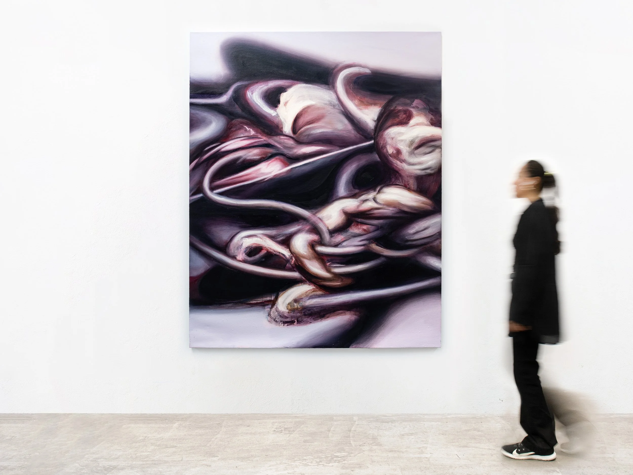 A person walking past an abstract purple and white painting in an art gallery.