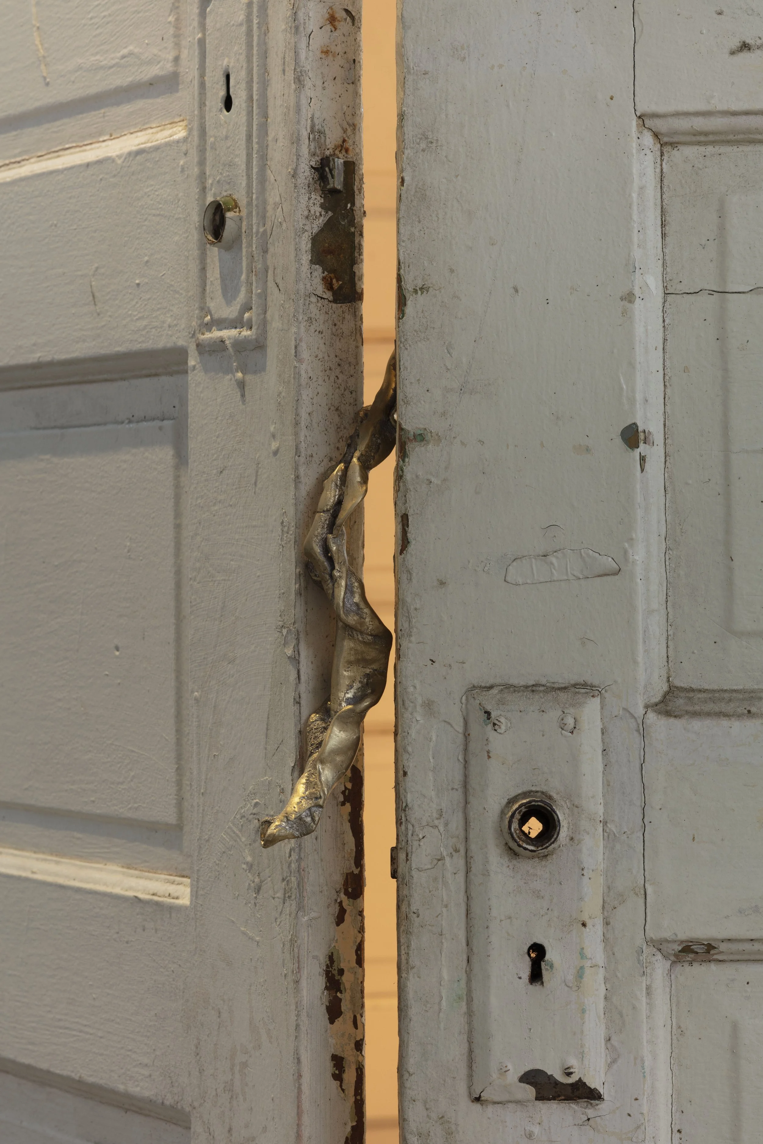 Close-up of a damaged and rusty door latch on a white-painted door, with peeling paint and visible rust spots.