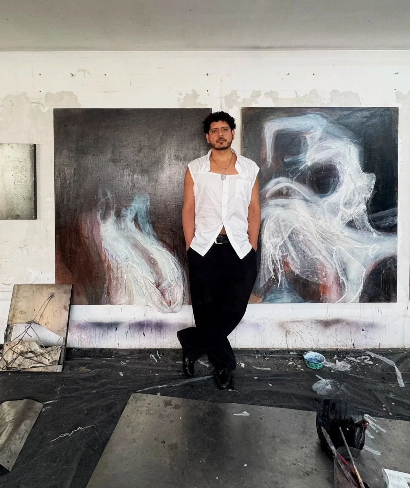 Rodrigo Ramírez Rodríguez standing in his studio in front of abstract paintings.