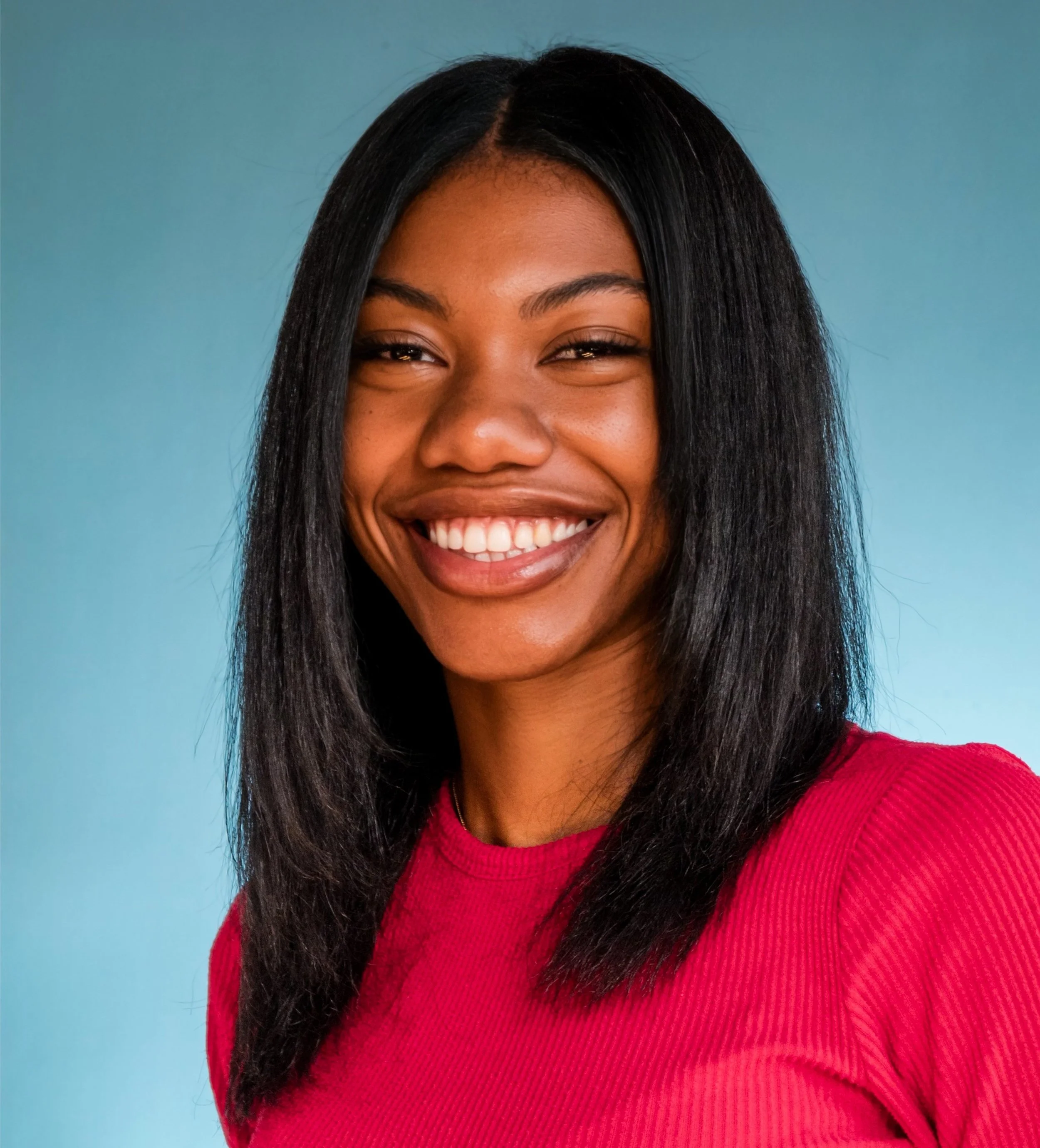 A smiling woman with straight black hair wearing a red shirt against a blue background.