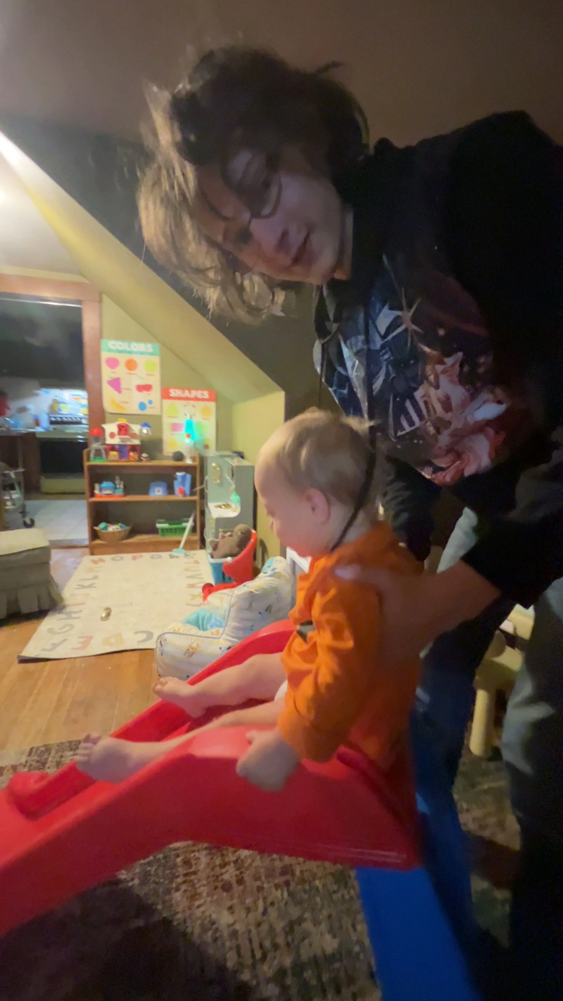 Alex helping Haiden go down his new play slide indoors.