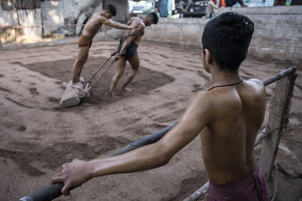 Traditional wrestling training with men preparing ground.