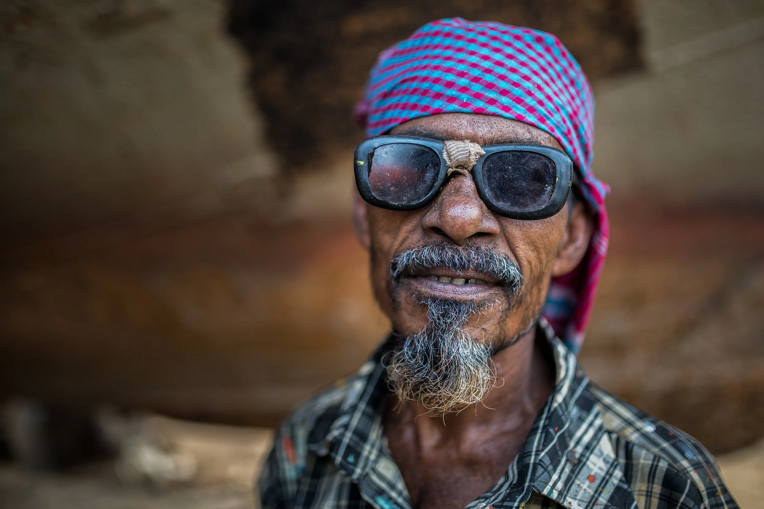Elderly man wearing sunglasses and a checkered headscarf