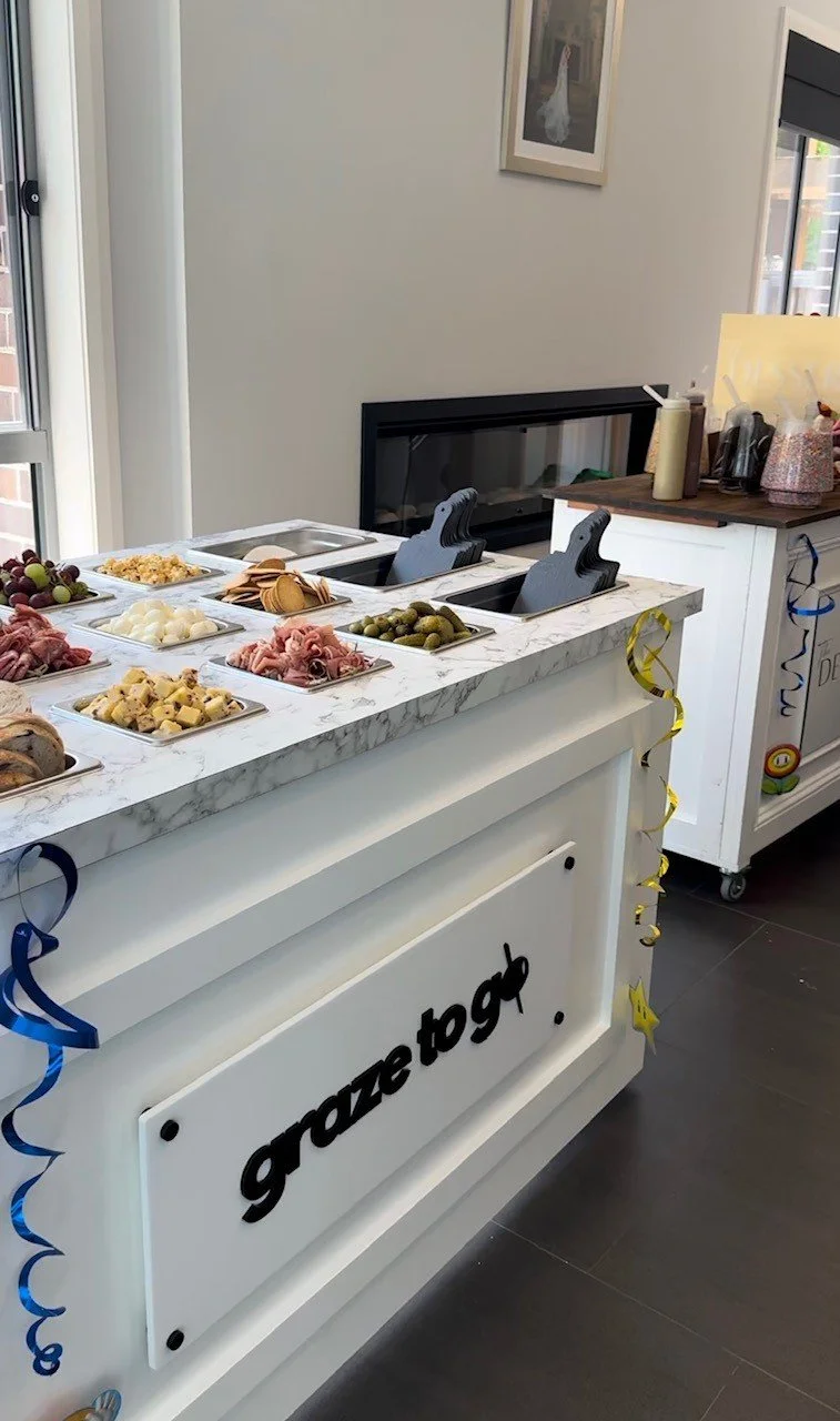 Counter with various appetizers including grapes, cheese, meat, pickles, and crackers at what appears to be a party or gathering.