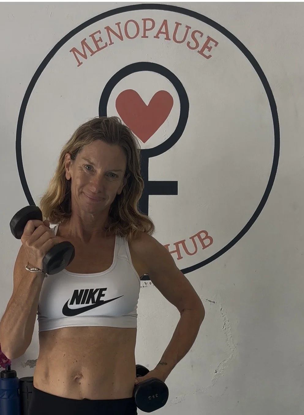 Charlotte birch menopause coach and pt Sitges in her boutique gym in front of menopause thrive hub logo