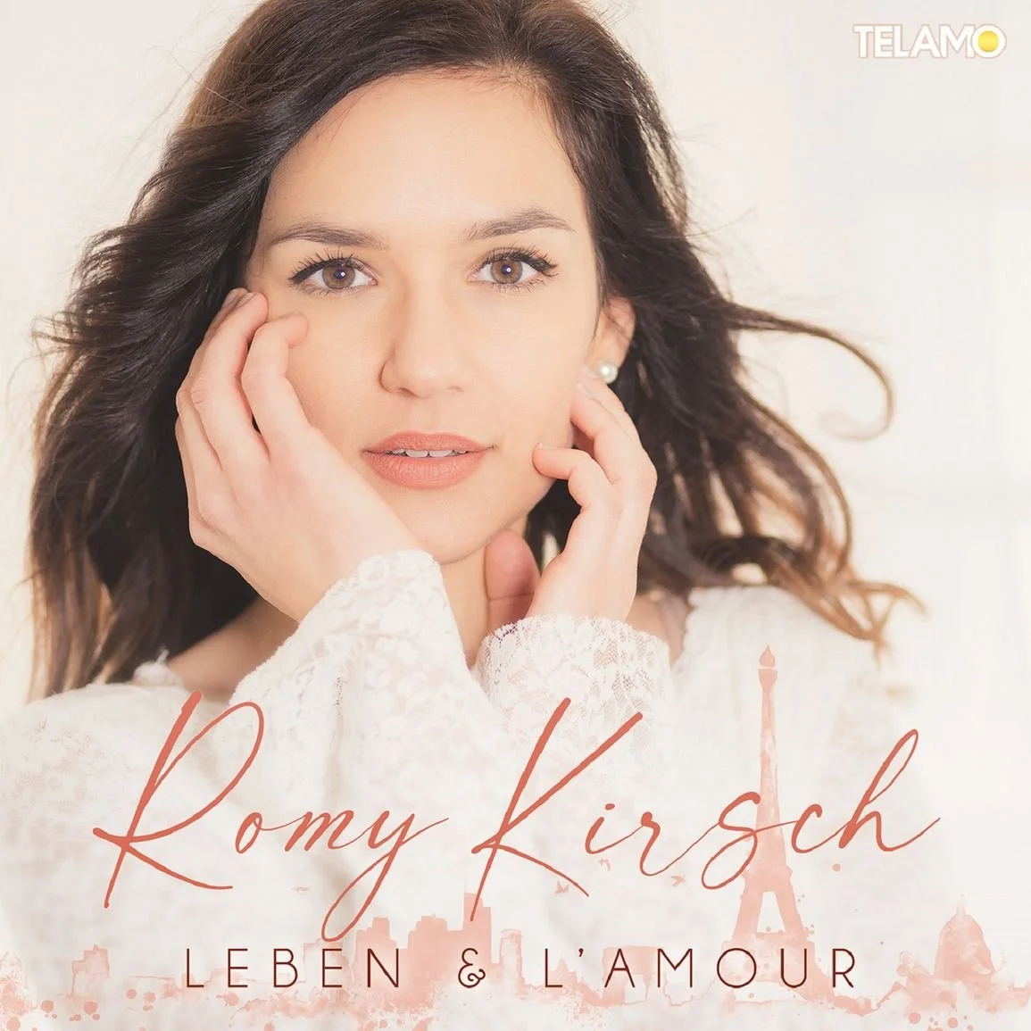Porträt von Romy Kirsc mit braunen, gewellten Haaren und hellen Haut, die Silber-Perlenohrringe trägt, vor hellem Hintergrund. Es gibt den Text 'Romy Kirsch' und 'Leben & L'amour' sowie eine schemenhafte Silhouette des Eiffelturms im unteren Bereich.