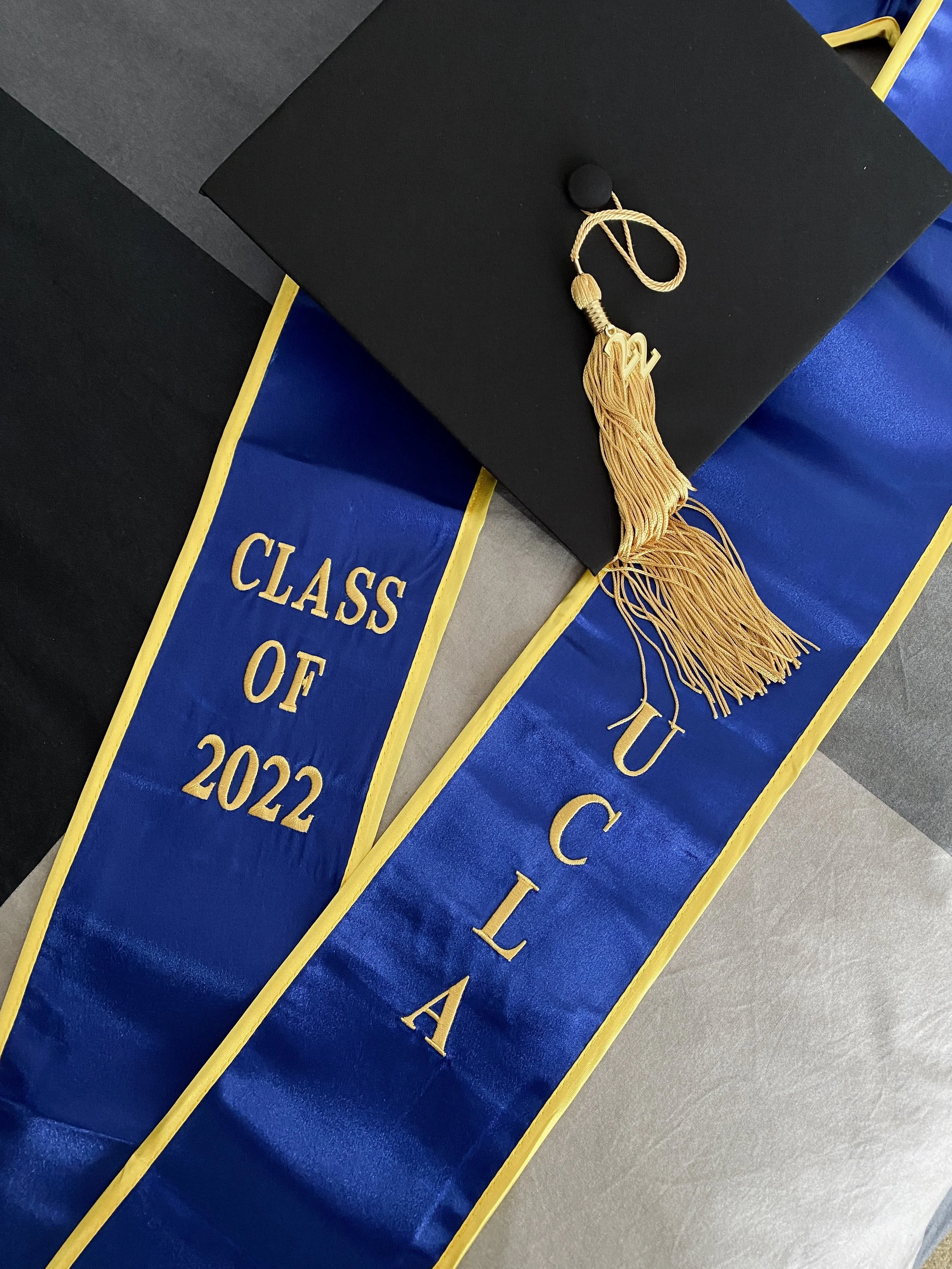 Anthea Guiost, chapeau de diplômé avec un pompon, posé sur un diplôme de fin d'études, avec des rubans bleus et jaunes indiquant la promotion class of 2022 de l'Université de Californie à Los Angeles (UCLA).