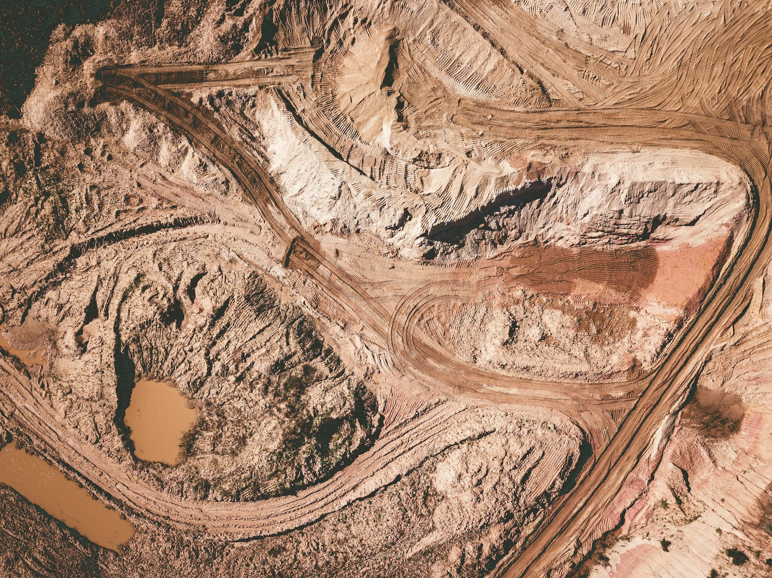 An aerial photograph of a red-brown open pit mine representing our hydrogeological impact assessment services