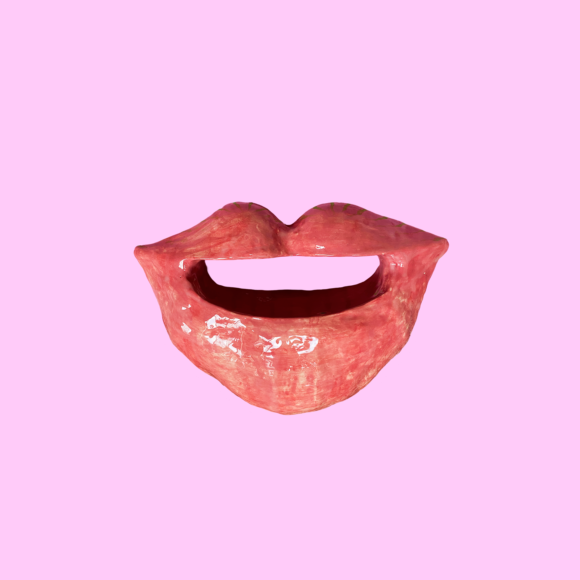 Keramik skulptur som kan fløjte, når man vipper den, vist på en lyserød baggrund.