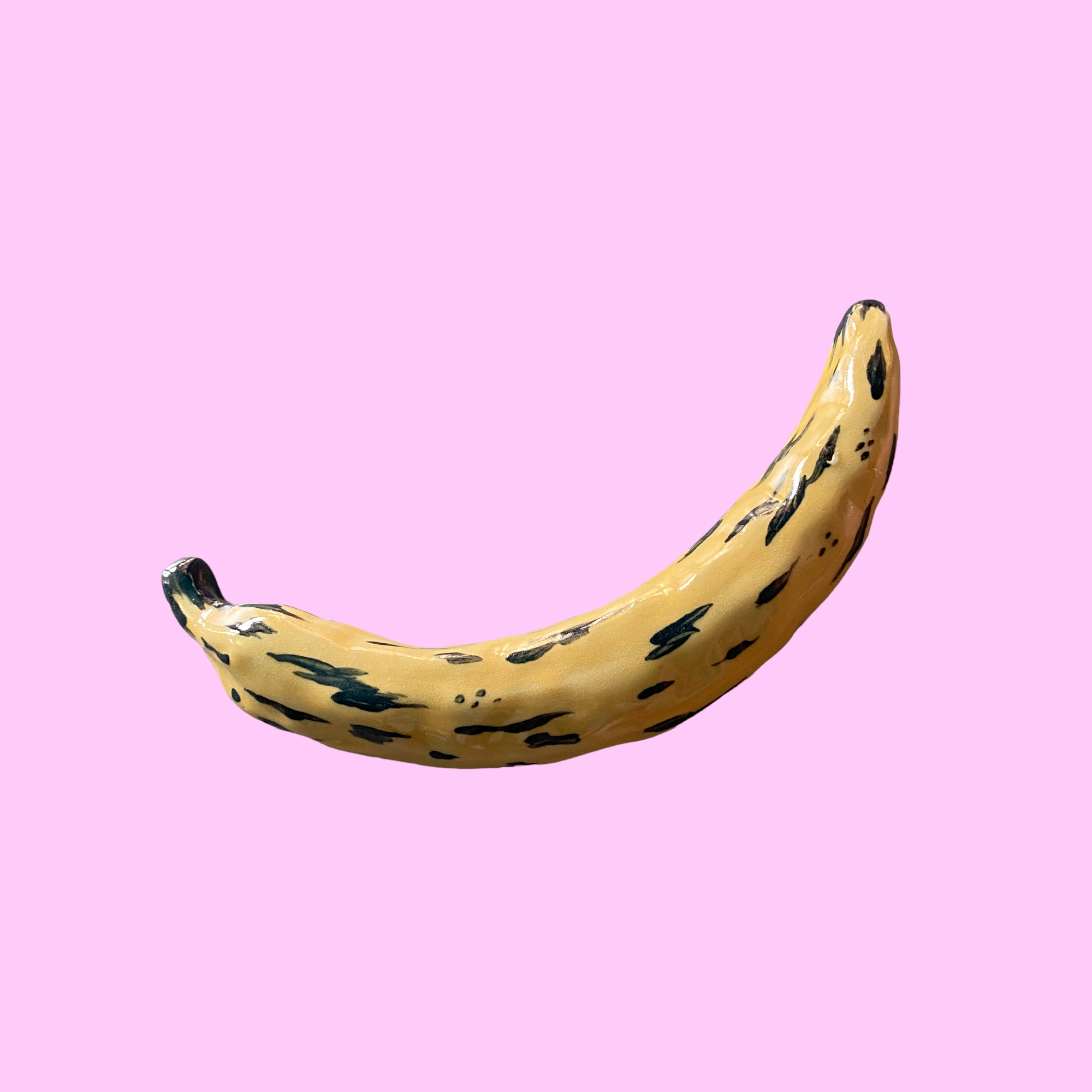 En banan med gule og sorte pletter mod en lyserød baggrund.