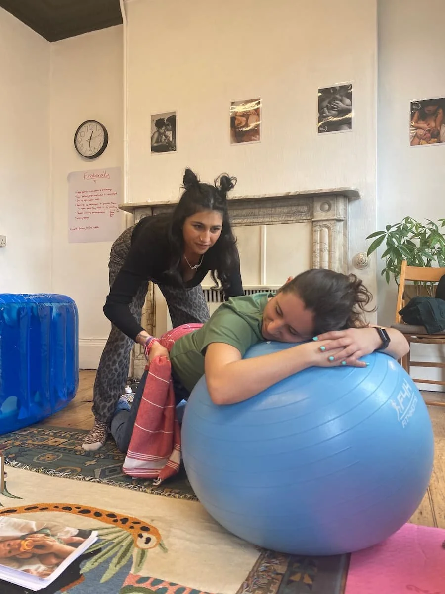 Atosa, birth and postnatal doula assisting a pregnant person on an exercise ball