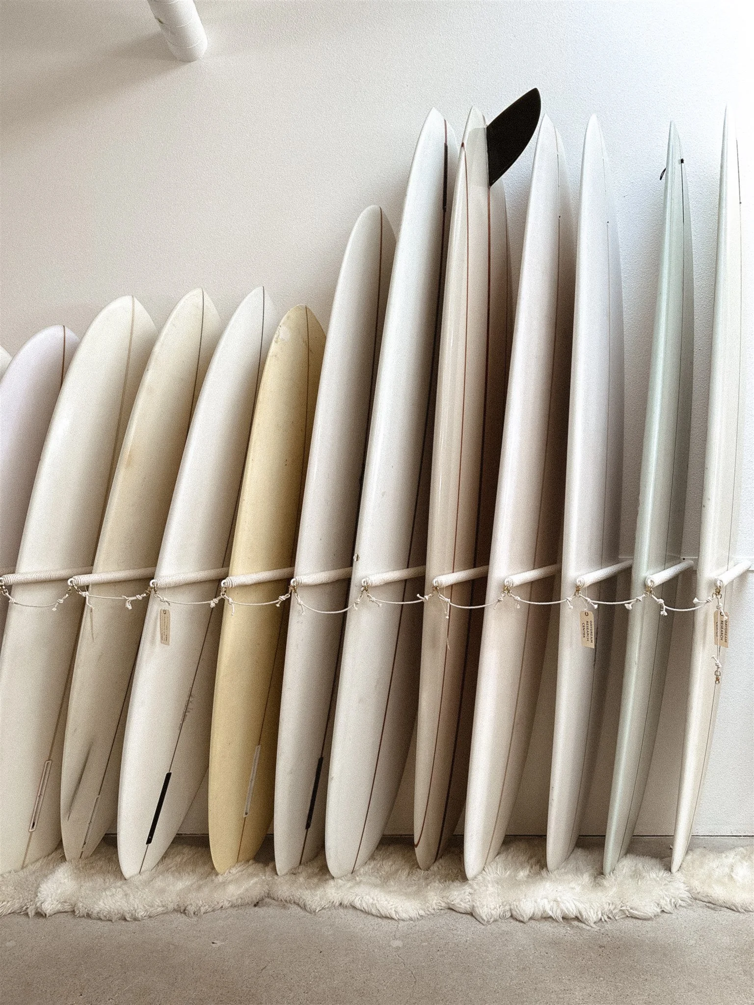 Row of white surfboards lined up against a wall
