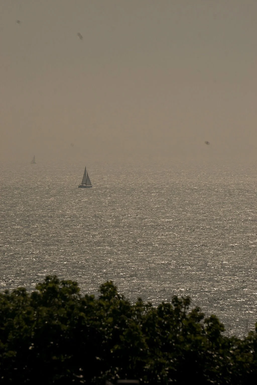 Lone sailboat on a hazy sea