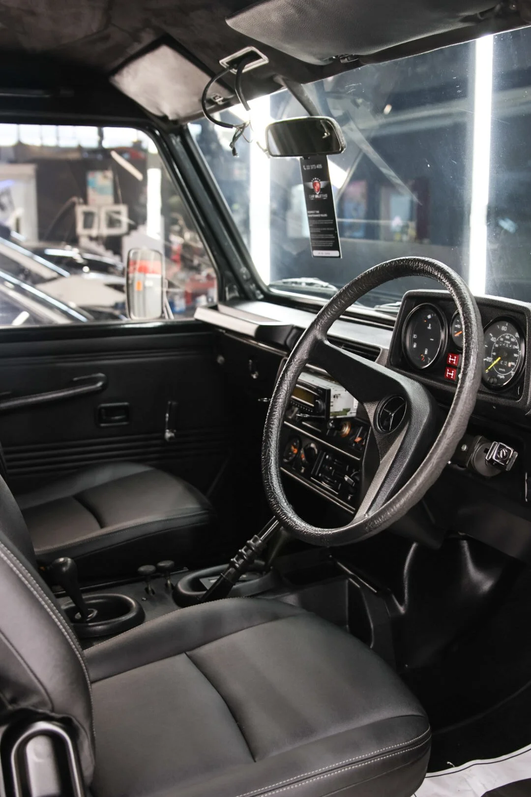 Interior of a vehicle showing the driver's seat, steering wheel, dashboard with gauges, and center console with controls.