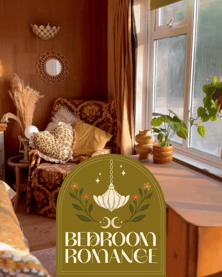 A cozy bedroom with a window letting in natural light, wooden furniture, decorative pillows, plants on the window sill, and a sign reading 'Bedroom Romance' with a hanging lamp, crescent moons, and floral accents.