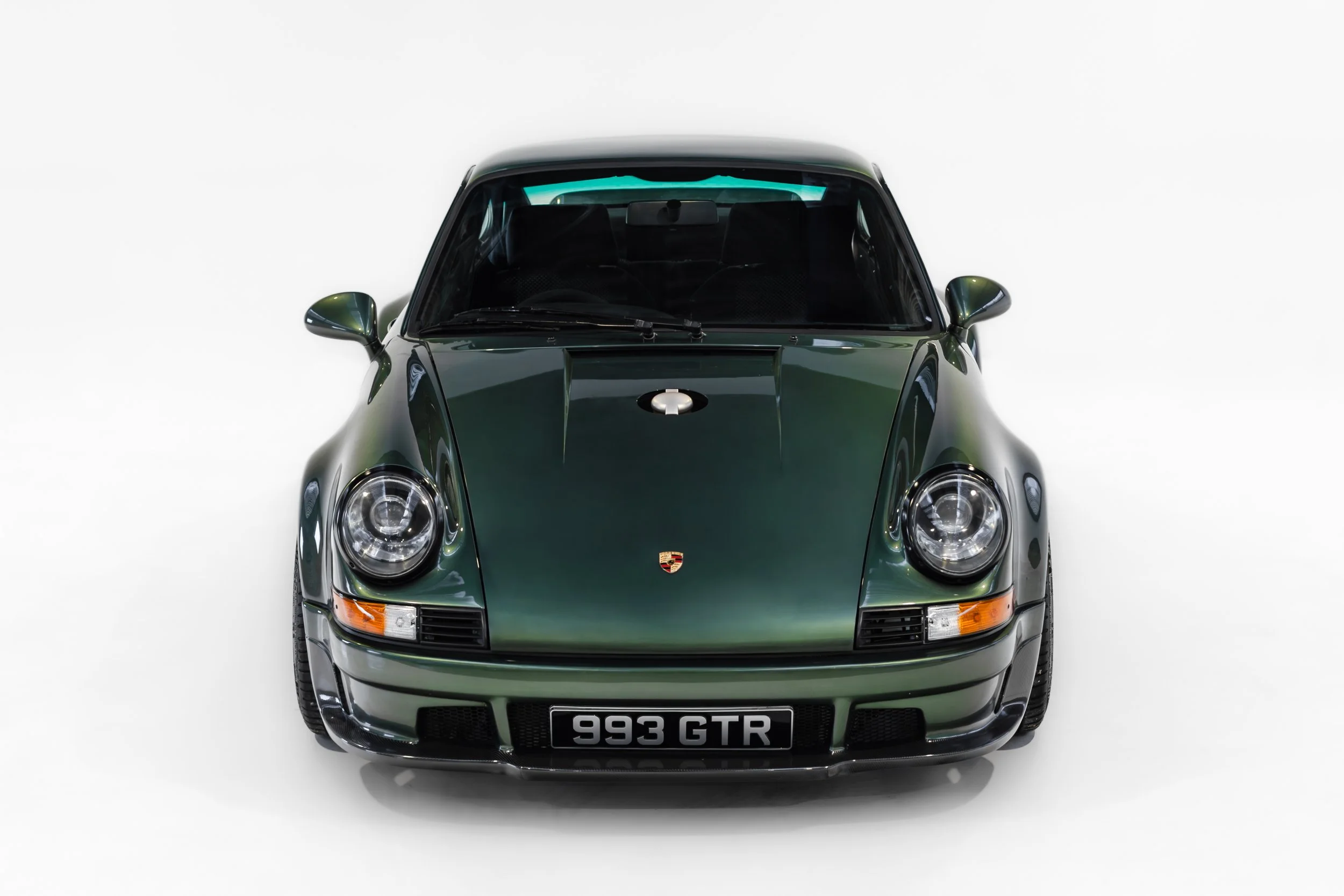 Front view of a dark green Porsche 993 GTR sports car against a white background.