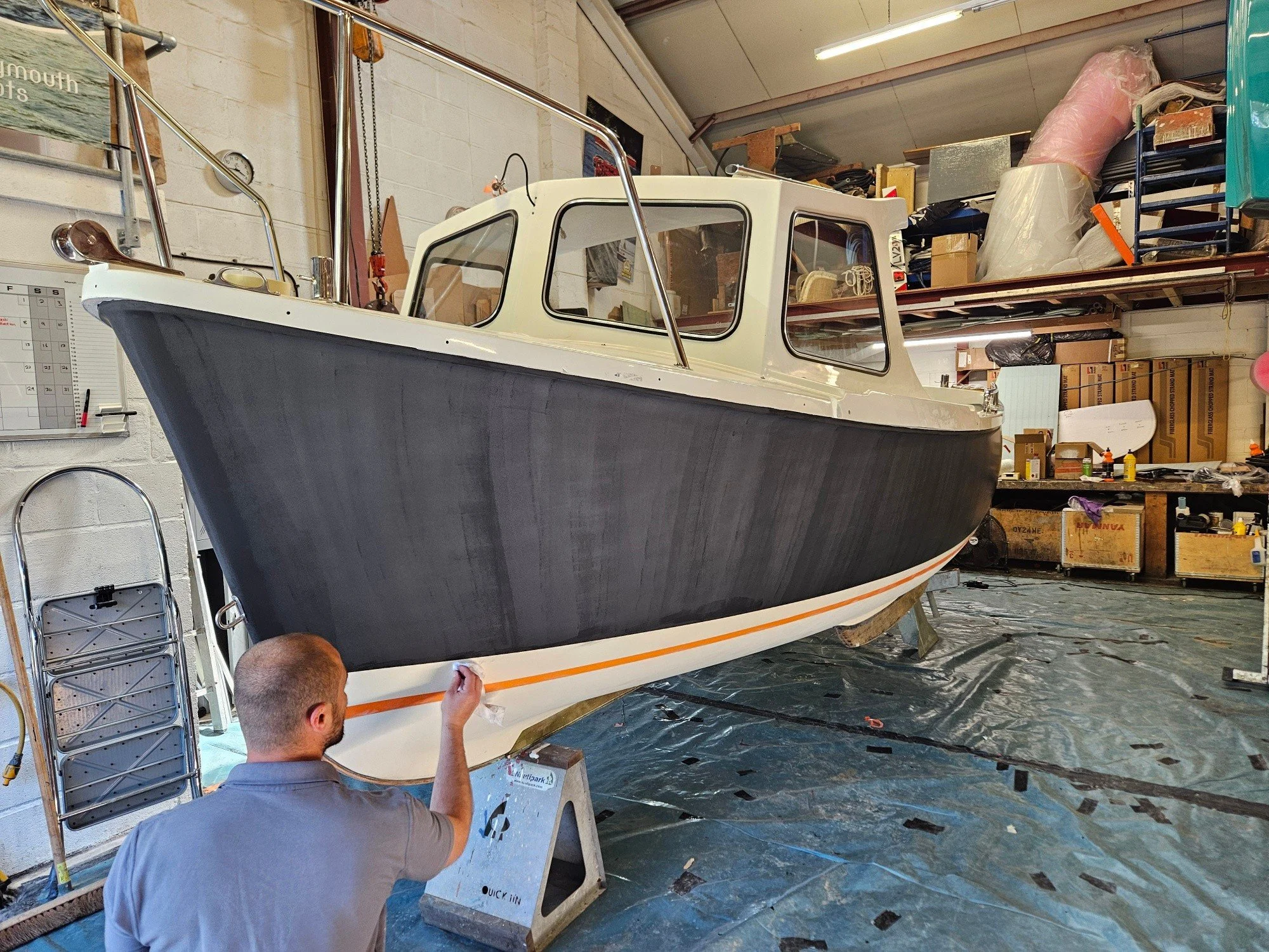 3 coats of black undercoat were applied yesterday. Here you can see us finishing up the sanding i. Preparation for the top coats.

Very odd seeing a hull in black!  By the end of the week, we should be finishing  the last coat of blue.