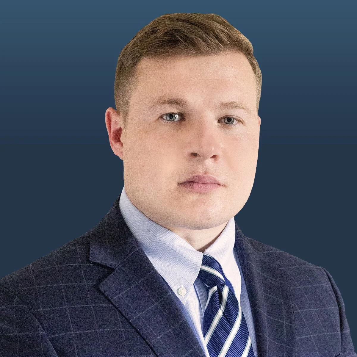 Professional headshot of blonde haired male attorney in navy suit against navy background