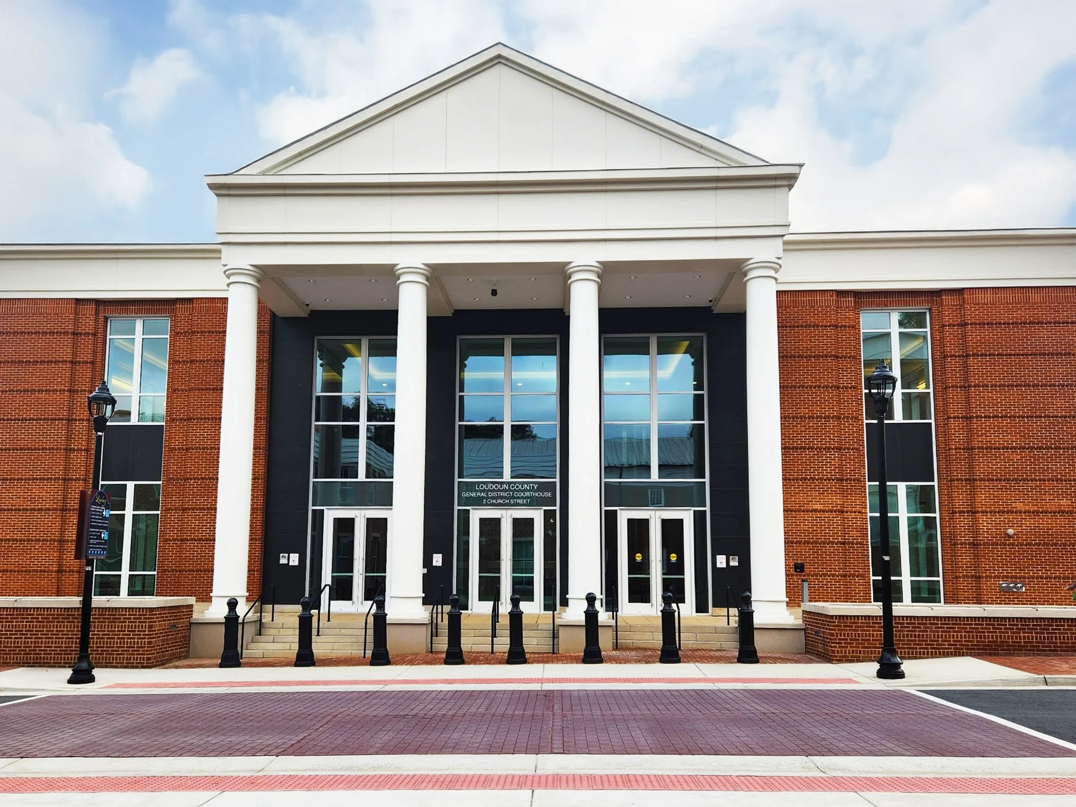 The Loudoun General District Brick Courthouse building with white trim against a blue cloud sky.