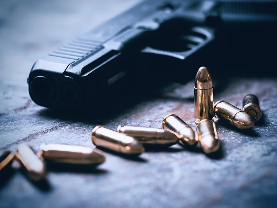 black handgun on gray brick surface with bullets next to it