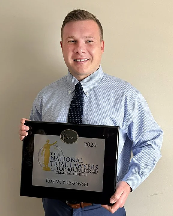 young male professional in blue shirt holding an award for Top Trial Attorneys 40 under 40