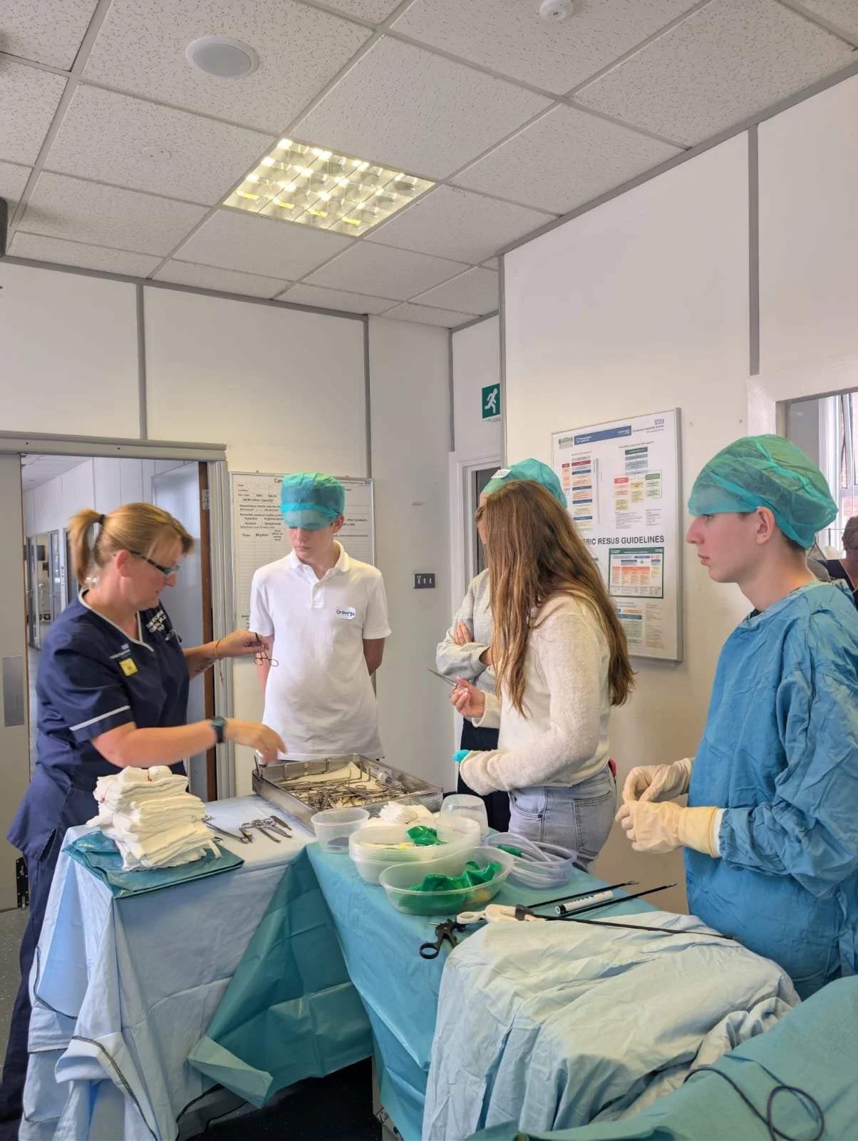 Medical professionals in scrubs and masks preparing surgical instruments in a hospital operating room.