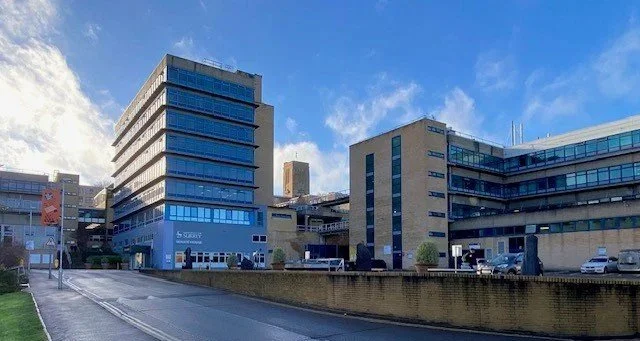 University of Surrey landscape with modern office buildings under a partly cloudy sky