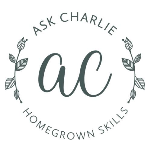 Logo with the words "Ask Charlie" and "Homegrown Skills," featuring a decorative circle of branches with leaves and wheat.
