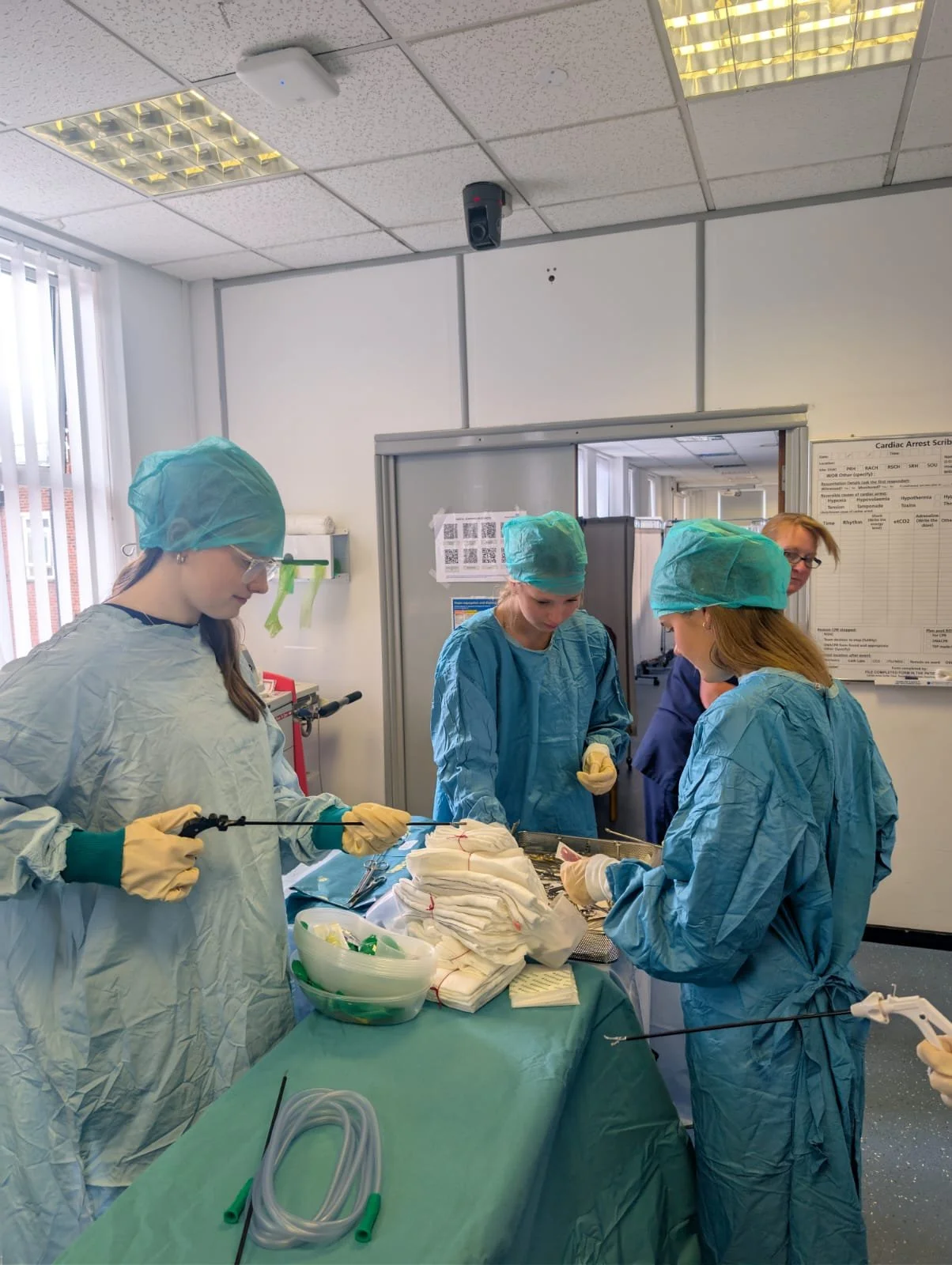 Medical team in scrubs and surgical caps performing a procedure in a hospital operating room.