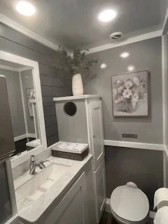 premium restroom trailer interior with sink vanity, mirror, decorative accents, and luxury amenities for weddings and special events