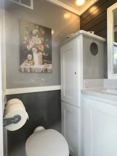 upscale restroom trailer interior featuring decorative artwork, premium lighting, a flushing toilet, and modern vanity