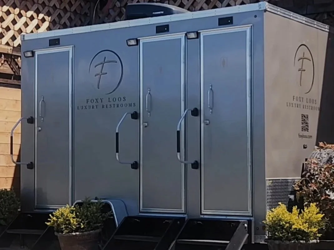 portable luxury restroom trailer  with three private stalls and steps at an outdoor event
