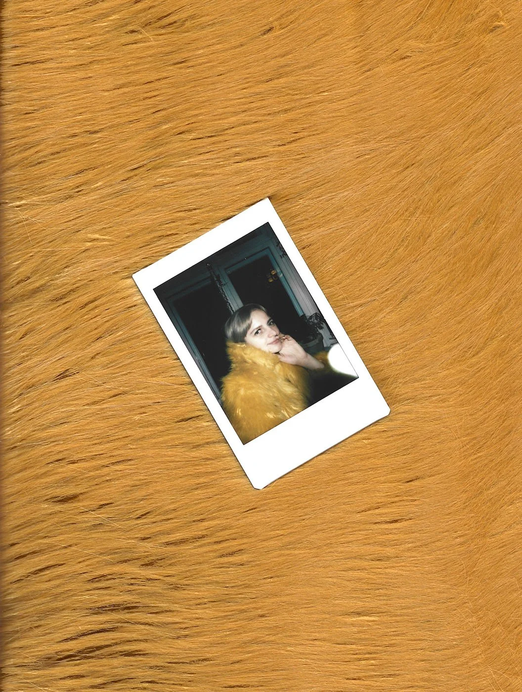 Fotografi af en kvinde med blondt hår, iført en gul pelsjakke, taget i et indendørsmiljø | Stemningsbillede | Filmproduktion i Aarhus | GESTALT