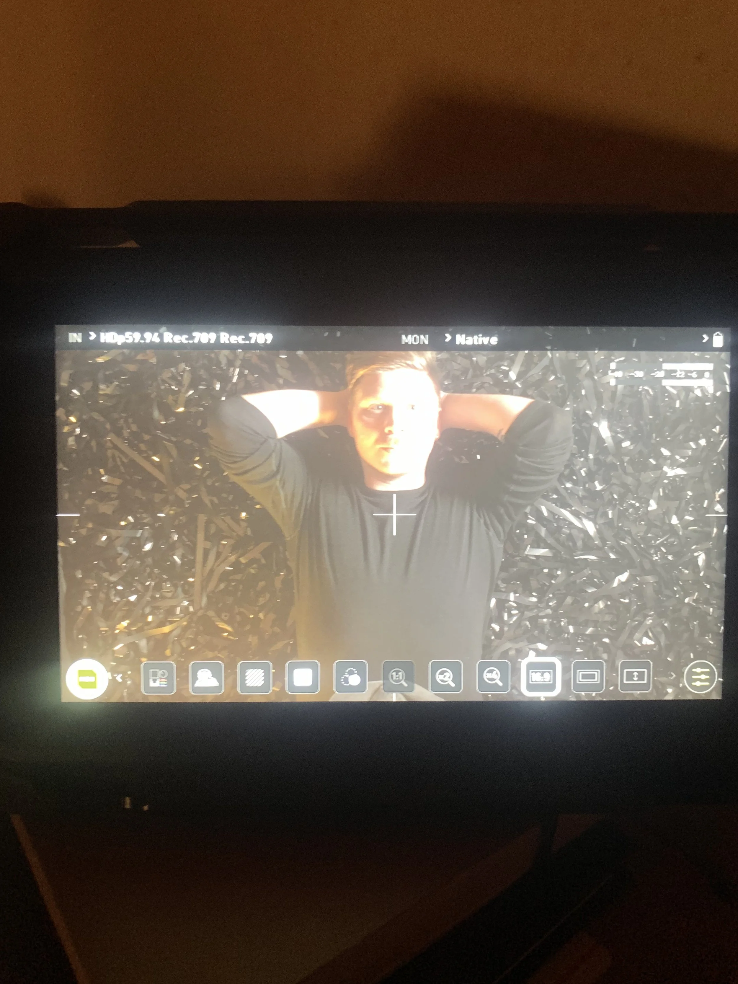 En person ligger ned med hænderne bag hovedet på en sort baggrund, set på en kameramonitor | Dokumentarfilm | Retrograd | Esben Persson & Anders Mielcke | Filmproduktion Aarhus | GESTALT