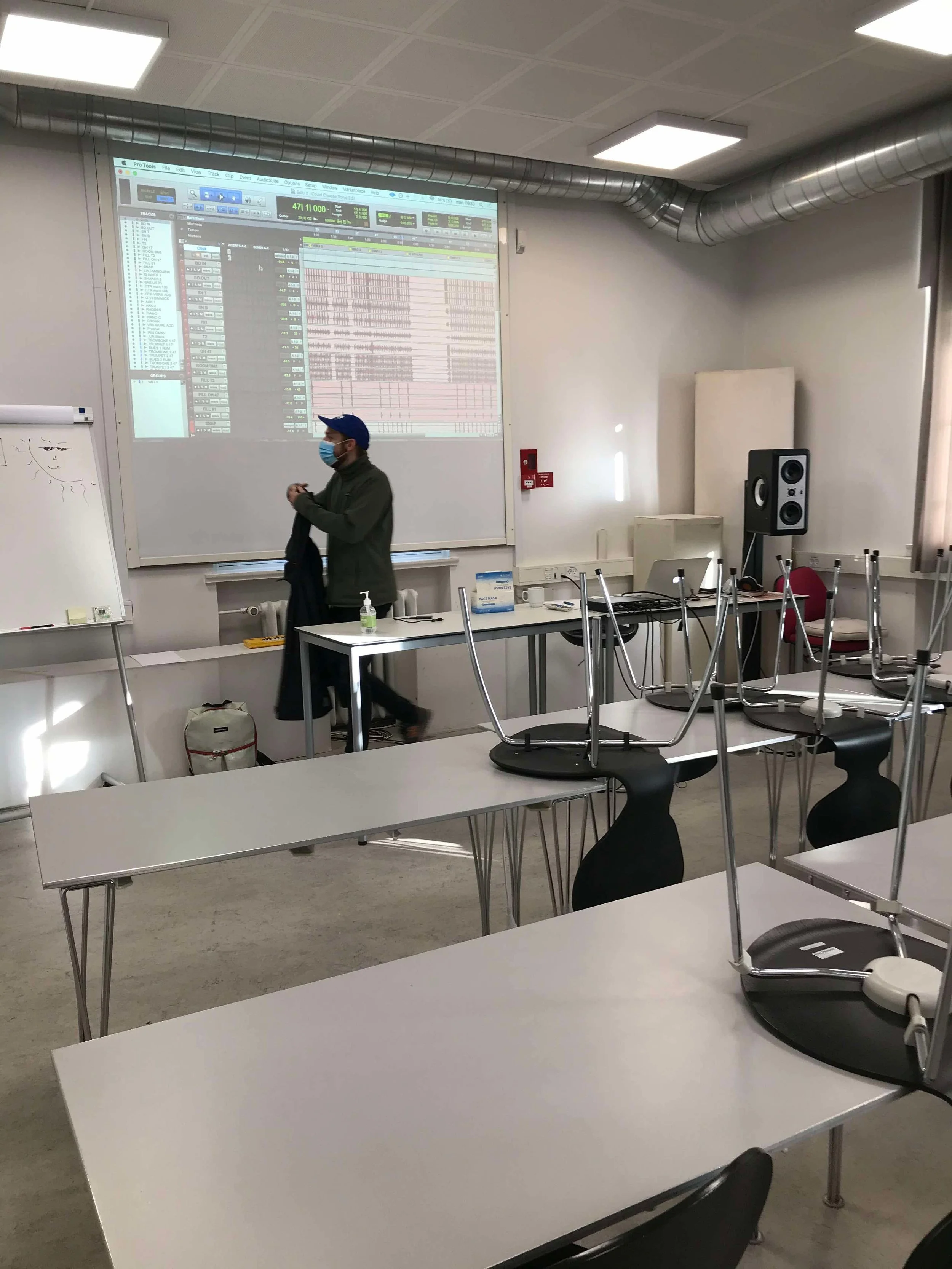 Et tomt klasseværelse med opslået tavle, borde og stole, hvor nogle stole er placeret med benene oppe på bordene | Musikkomposition | Studieproduktion og lyddesign | Filmproduktion Aarhus | GESTALT