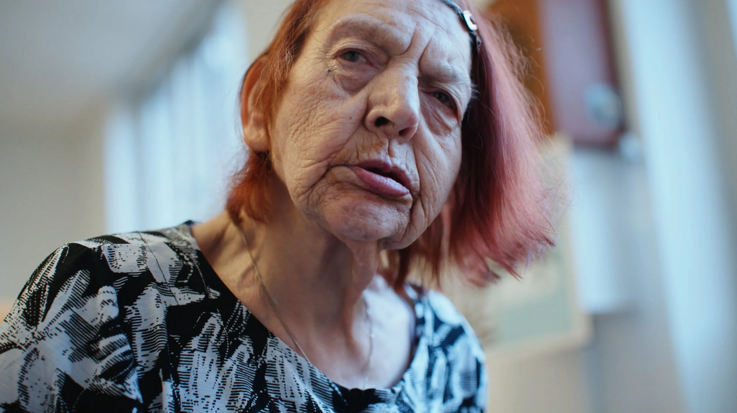 Nærbillede af en ældre kvinde med rødligt hår | Dokumentarfilm | Stemmer fra sær- og åndssvageforsorgen | Anders Mielcke Grønbæk | GESTALT
