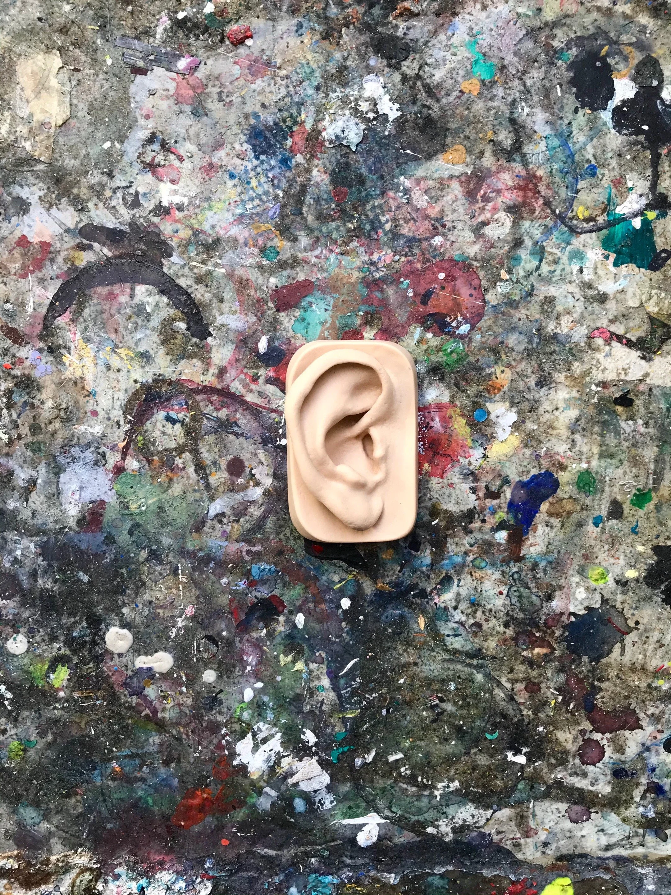 En skulptur af et menneskeøre placeret på en farvet og plettet værkstedsbord | Kortfilm | Wild Wild Vesløs | Esben Persson | Filmproduktion Aarhus | GESTALT