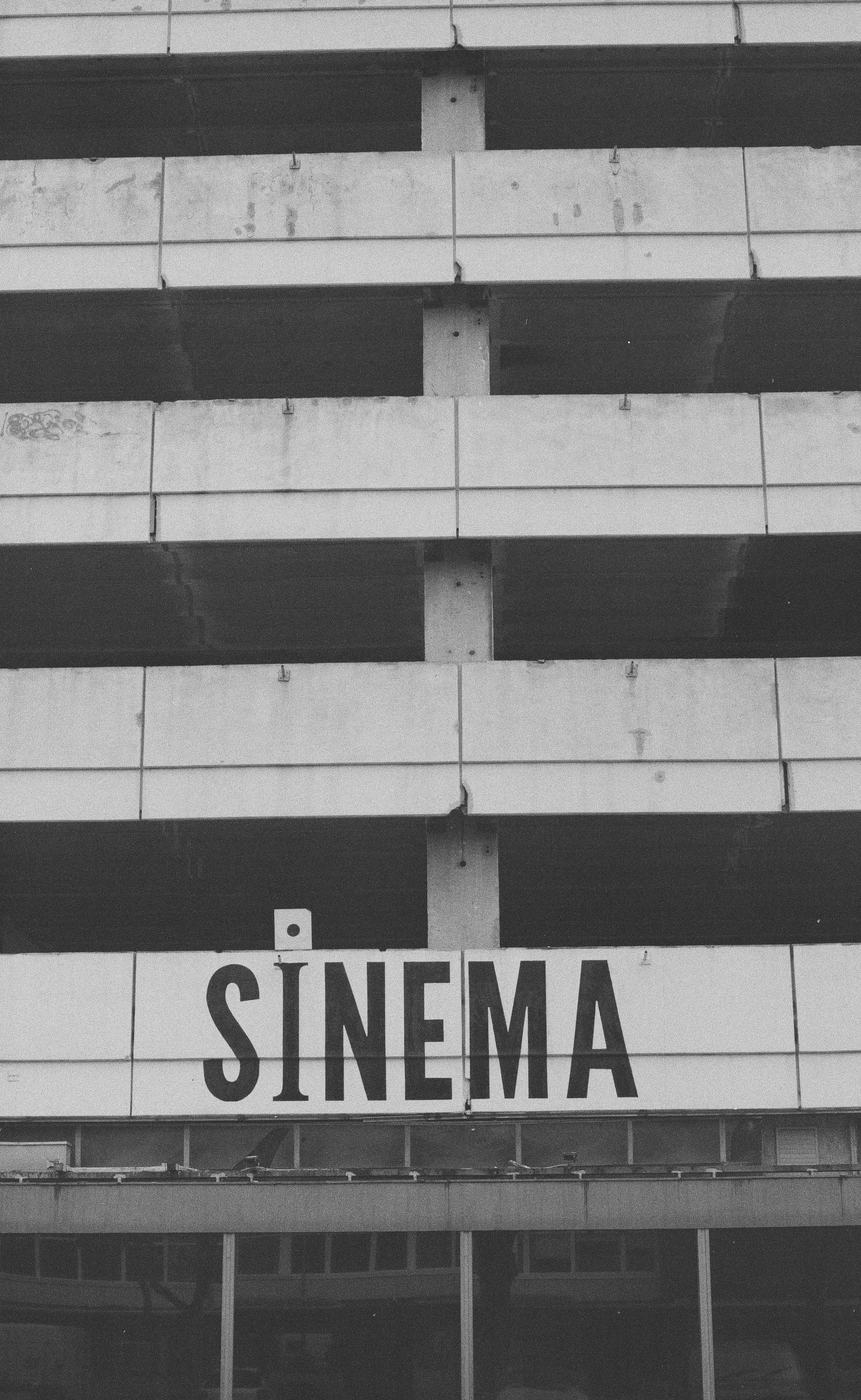 En sort-hvid billede af en bygning med et skilt, der siger "SINEMA" i store bogstaver | Location scouting | Kodak | Filmproduktion Aarhus | GESTALT