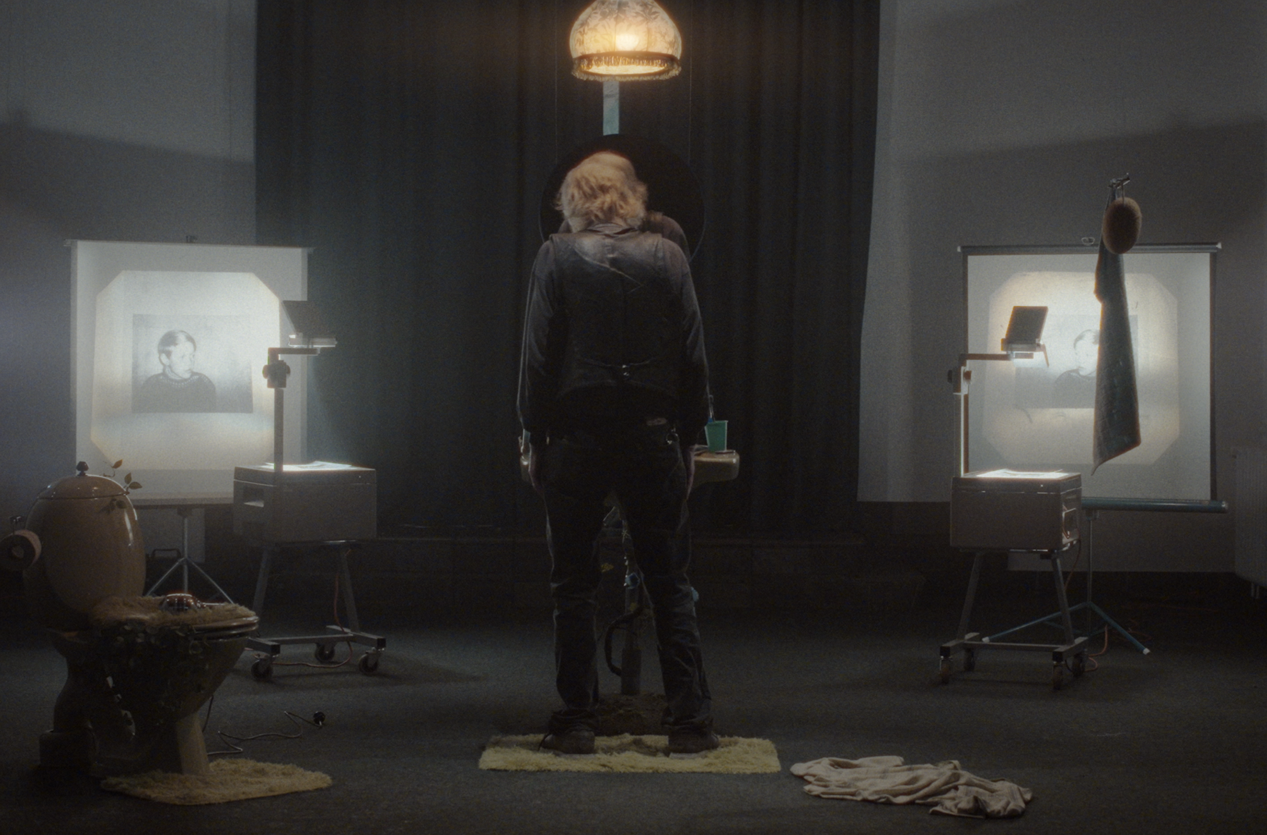 En person står foran to lærreder med sorte og hvide billeder med et barndomsbillede | Dokumentarfilm | Retrograd | Esben Persson & Anders Mielcke | Filmproduktion Aarhus | GESTALT