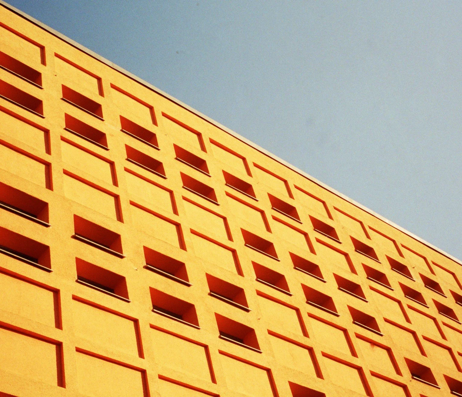 En gul bygning med en geometrisk mønster af vinduer mod en klar blå himmel | Location scouting Berlin | Kodak | Filmproduktion Aarhus | GESTALT