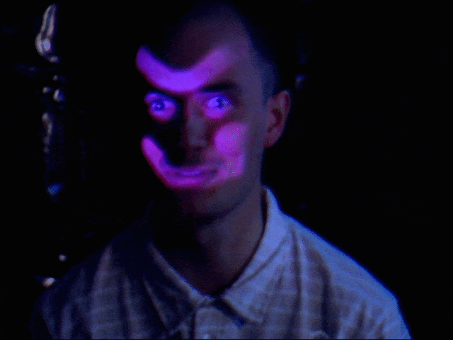 Et menneske med mørkt hår i en lys skjorte, oplyst af neonlys med skiftende farver, der skaber en surrealistisk effekt | Testoptagelser | Filmproduktion | GESTALT