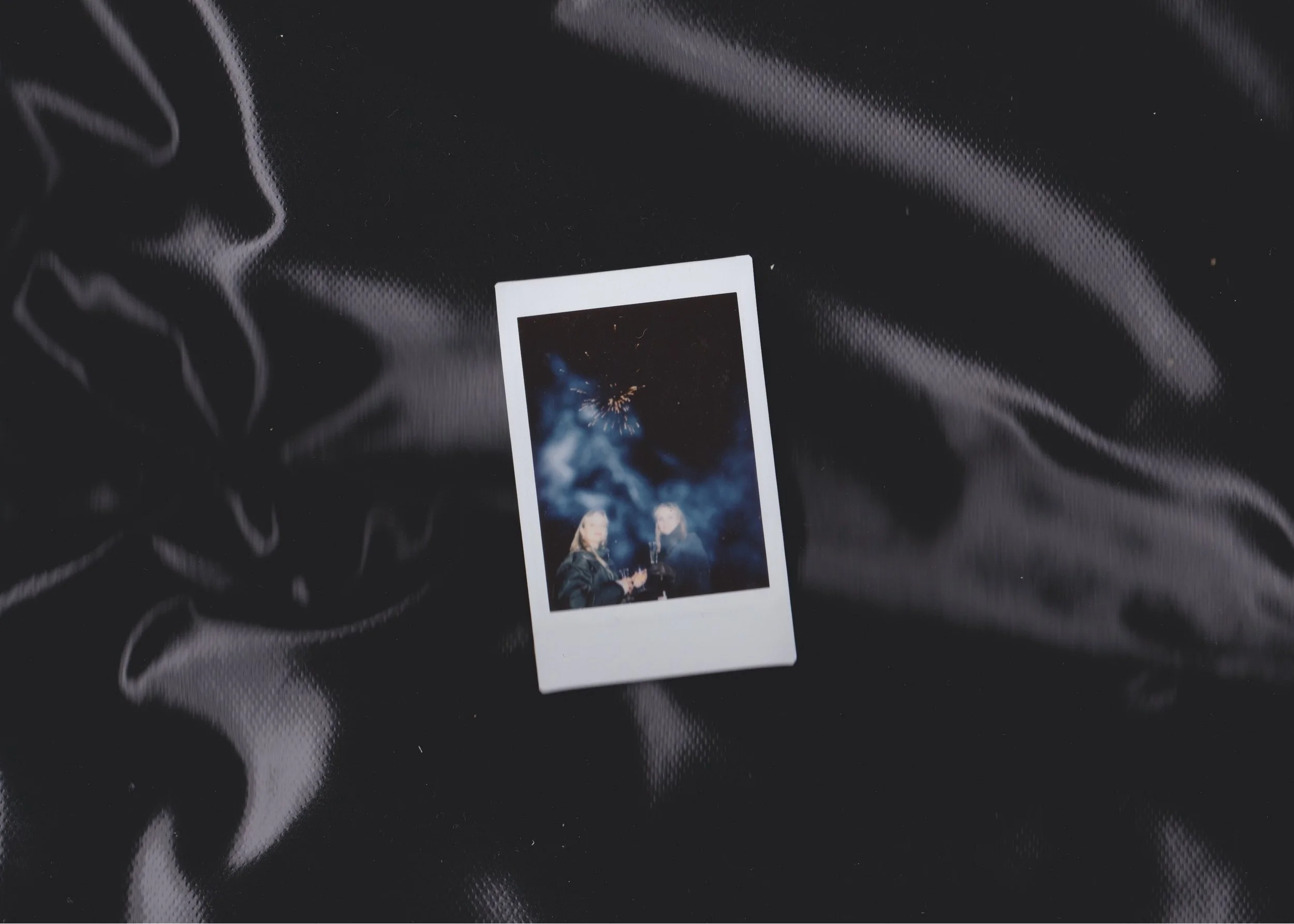 En scanning af et Polaroid-billede, der viser to personer, der drikker champagne under fyrværkeri på nattehimlen | Fælleskab og behind the scenes | Filmproduktion Aarhus | GESTALT