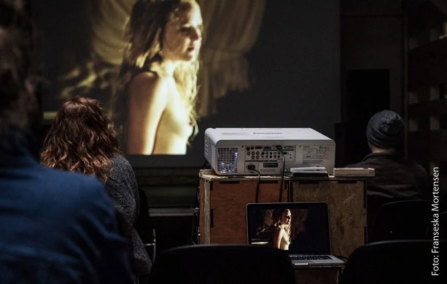 Folk, der ser en film på et projektor i et mørkt rum | Film- og fotofestival på Aarhus Kunstakademi ved navn Aarhus Independent Pixels | Eventbilleder | GESTALT